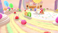 Kirby rolling around on a cake-based stage, with a candy Gordo in the frame and a breakable wall in the background