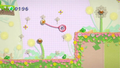 Kirby hanging from a dandelion seed in a pre-release version of the game